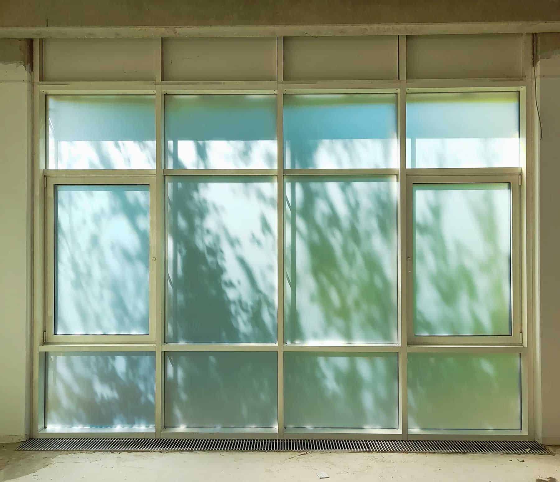 Mehrteiliges bodentiefes Fenster komplett beklebt mit Milchglasfolie für absoluten Sichtschutz nach Tisax Zertifizierung.